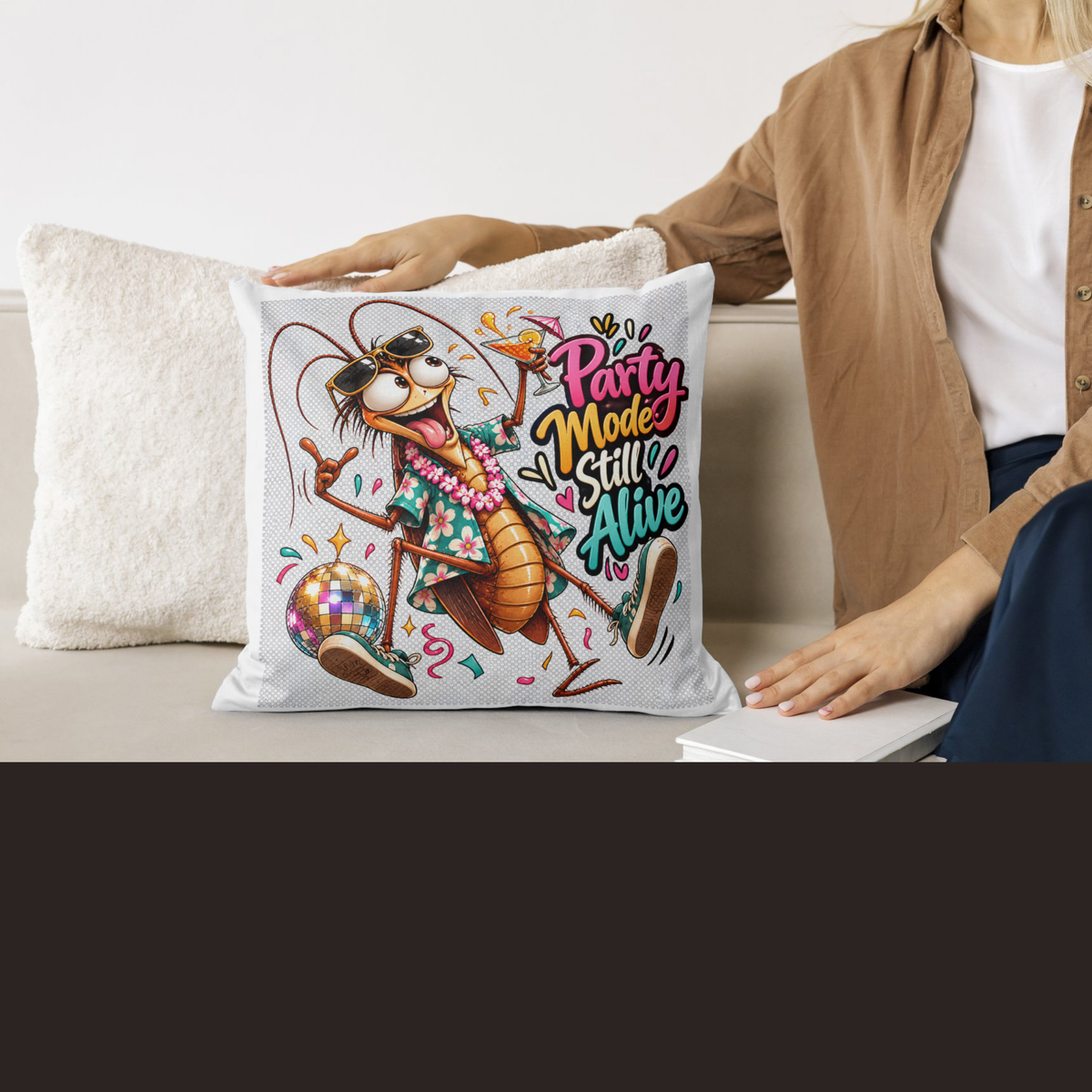design mock ups. Design can be used on t-shirt, mug, wall paper, sticker, and more. A square throw pillow with a colorful cartoon cockroach graphic and the text 'Party Mode Still Alive' is held by a person sitting on a couch next to another white pillow.