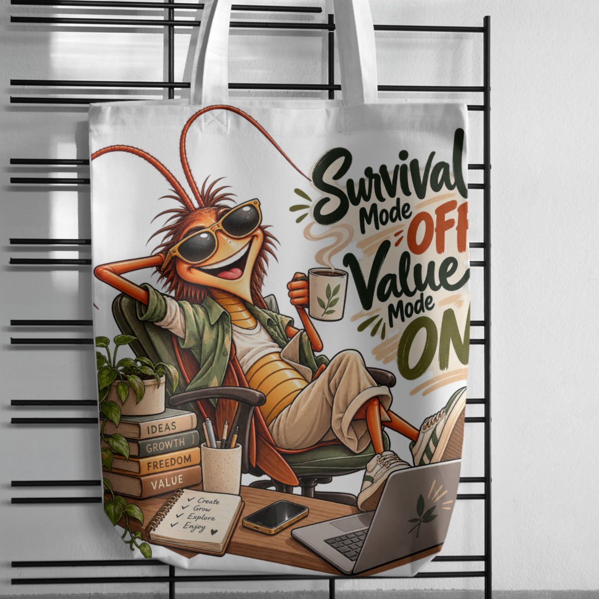 design mock ups. Design can be used on t-shirt, mug, wall paper, sticker, and more. A white canvas tote bag with white shoulder straps, featuring a colorful cartoon illustration of a cockroach wearing sunglasses and lounging in an office chair with the text 'Survival Mode OFF Value Mode ON'. The bag is displayed hanging against a black metal grid rack.